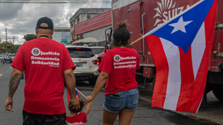 Familia de trabajadores de la Suiza Dairy portando una bandera de Puerto Rico